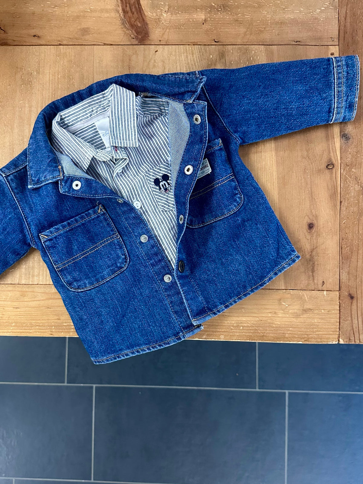 Jeansjacke mit gestreiftem Hemd auf Holzboden